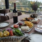 Elegantly set table with wine and gourmet dishes, offering a picturesque view of the landscape.