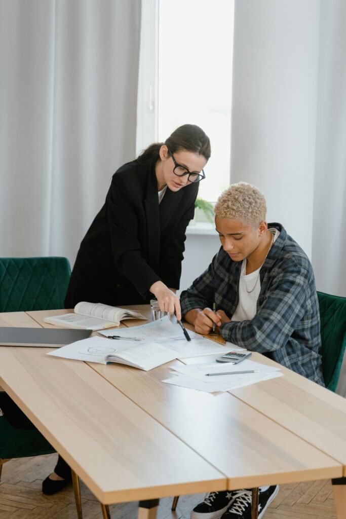 A focused learning moment between a teacher and student discussing at a desk.